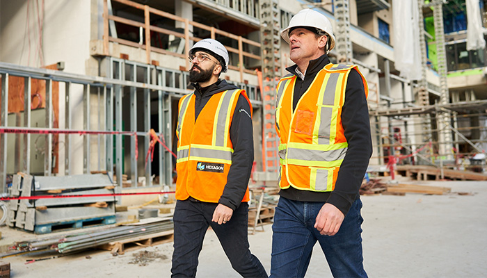 Hexagon client in high-vis vest and hard hat walking a busy construction site